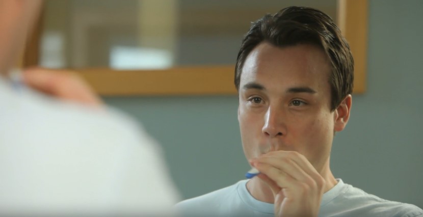 Man brushing teeth while looking at mirror